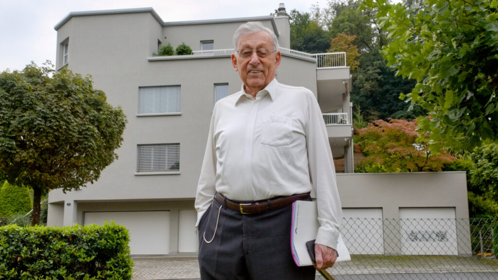 Mann vor Mehrfamilienhaus