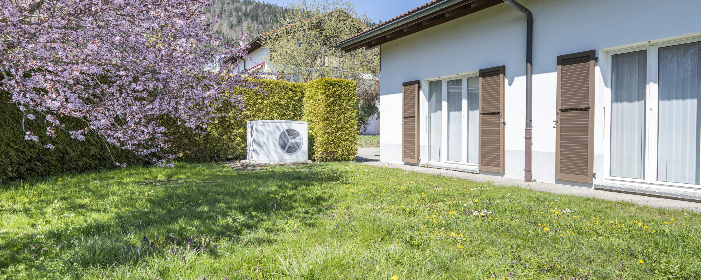 eine Wärmepumpe im Garten neben einem Haus