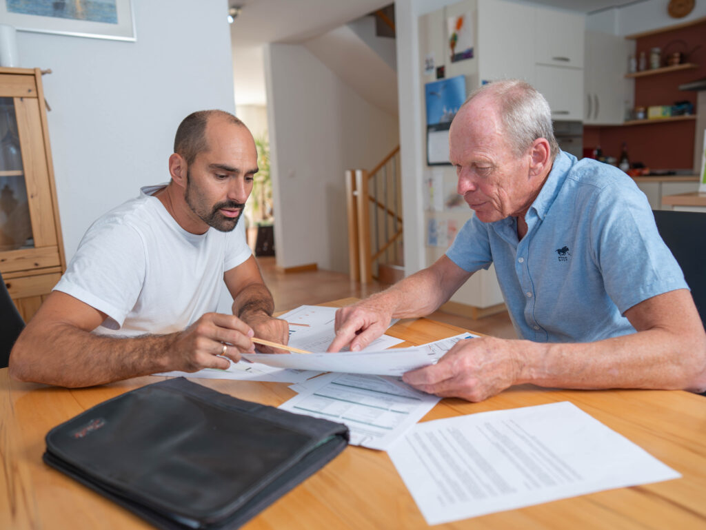 due uomini seduti al tavolo esaminano dei documenti